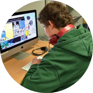 A photo of a participant with his back to the camera, with a hoodie on and red ear phones, using a computer.